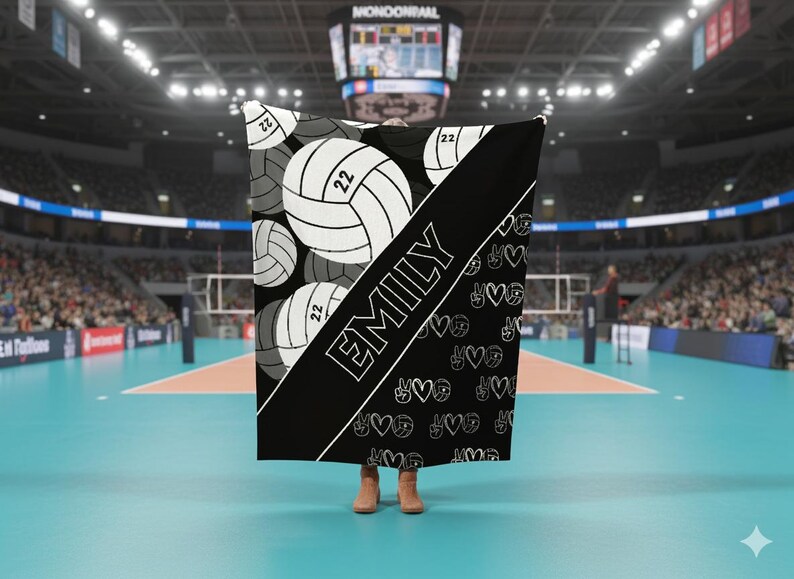 Puede incluir: Una manta en blanco y negro con un patr&oacute;n repetitivo de balones de voleibol con el n&uacute;mero 22. Una franja negra diagonal en el centro muestra el nombre EMILY en letras may&uacute;sculas blancas, junto a un peque&ntilde;o patr&oacute;n de corazones y signos de paz.
