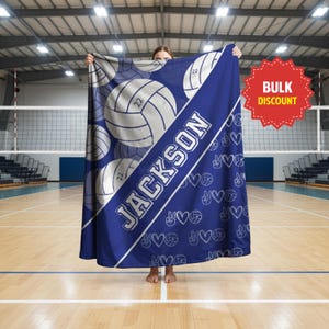 Puede incluir: Una manta azul con un patr&oacute;n repetitivo de balones de voleibol blancos con el n&uacute;mero 22, el nombre JACKSON en letras may&uacute;sculas blancas grandes y un patr&oacute;n m&aacute;s peque&ntilde;o de corazones, signos de paz y balones de voleibol blancos.
