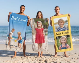 May include: Three people holding personalized beach towels on a sunny beach. One towel is blue with "Best Friend" text and a photo of children. Another is a photo of a girl in a red dress. The third is yellow with "James & Emma" text and photos.