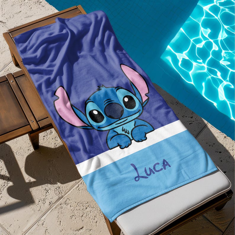 May include: A blue beach towel featuring the character Stitch from Lilo & Stitch. The towel has a large image of Stitch, with pink ears and a blue body, on a dark blue background. The name "Luca" is written in purple script on a light blue stripe.