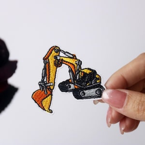 Könnte beinhalten: Gelber und schwarzer gestickter Bügeleisen-Aufnäher mit einem Bagger mit Schaufel.