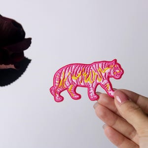 May include: Pink and yellow embroidered iron-on patch of a tiger walking.
