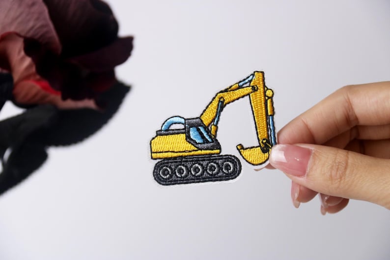 Pu&ograve; includere: Toppa ricamata gialla di un escavatore con un cingolo nero e dettagli blu.