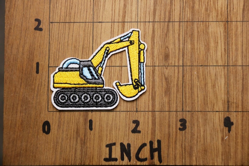 Pu&ograve; includere: Toppa ricamata gialla da stirare con un escavatore con cingoli neri e una cabina blu. La toppa &egrave; larga circa 5 cm.