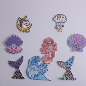 Pode incluir: Um conjunto de nove patches bordados para passar a ferro com uma variedade de designs de temática marítima, incluindo uma sereia, um unicórnio, uma concha e uma onda.