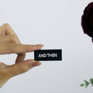 May include: A black fabric patch with white embroidery that reads "AND THEN".