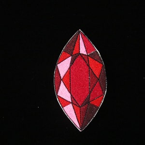 May include: A red and pink gemstone with a faceted design. The gemstone is embroidered on a black fabric.