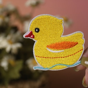 May include: Yellow embroidered iron-on patch of a rubber ducky with orange beak and feet, floating on blue water.