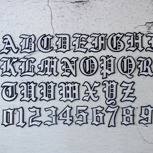 May include: White letters and numbers in a gothic font style on a white textured background. The letters are A through Z and the numbers are 0 through 9.