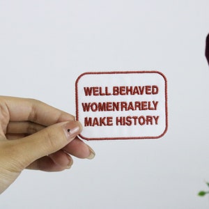 May include: White embroidered patch with red stitching. The patch reads "Well Behaved Women Rarely Make History."