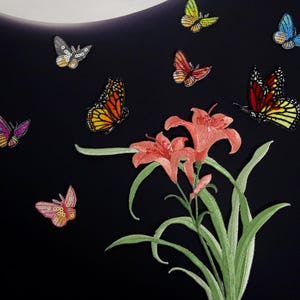 May include: A black background with a pink, orange, and yellow butterfly, a red, orange, and yellow butterfly, a gray butterfly, and a blue butterfly. There are also pink flowers with green leaves.