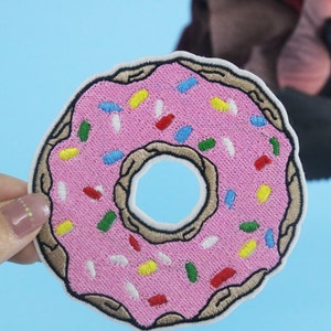 May include: Pink embroidered donut patch with colorful sprinkles.