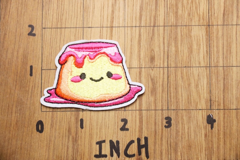 Peut inclure: Un patch brod&eacute; thermocollant repr&eacute;sentant un pudding en dessin anim&eacute; avec un visage souriant. Le patch mesure environ 5 cm de large.