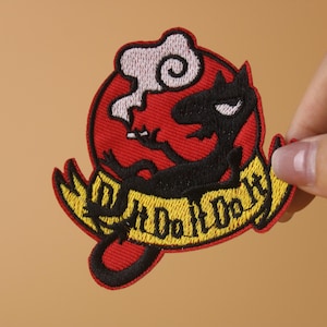 May include: A red, black, and yellow embroidered patch featuring a cartoon character with a smoke cloud above its head. The character is holding a cigarette and the text "Don't Do It" is written on a yellow banner.