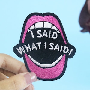 May include: Pink embroidered patch with a black mouth and white teeth. The text "I SAID WHAT I SAID!" is embroidered in white on the patch.