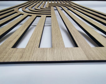 May include: A wooden wall decor panel with a geometric design featuring black lines and a curved pattern. The panel has a light brown wood grain finish.