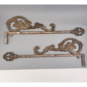 May include: Two ornate, antique-style metal keys with intricate scrollwork and floral details. The keys are a muted silver color with a distressed finish, suggesting age and use. The keys are mounted on a gray background.