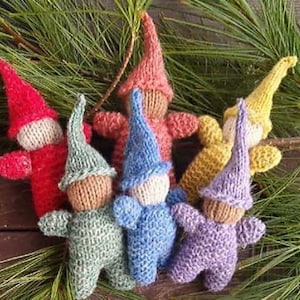 May include: Six knitted gnome ornaments in various colours, including red, green, blue, purple, and yellow. Each gnome has a pointed hat and a white face.