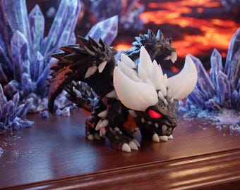May include: A small, black dragon figurine with white crystalline horns and spikes along its back. The creature features glowing red eyes, a textured dark body, and small wings, standing in a quadrupedal pose with sharp white claws on its feet.