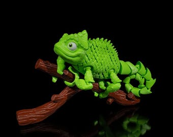 May include: A bright green chameleon figurine perched on a brown branch against a black background. The lizard has a textured body, a curled tail, and is posed with its front legs gripping the branch. The branch is a dark brown color.