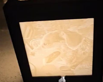 May include: A black, cube-shaped lamp with illuminated panels displaying a dog portrait. The lamp has a warm, soft glow, and a white power cord extends from the base. The panels appear to be made of a translucent material.