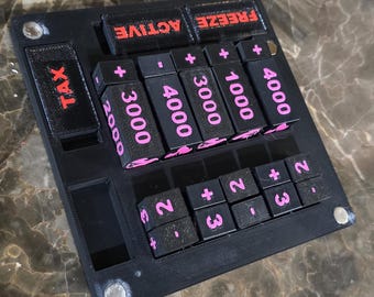 May include: A black electronic device with pink and red text. The device has several buttons labeled "TAX", "ACTIVE", and "FREEZE". Other buttons display numbers like "2000", "3000", "4000", and "1000".