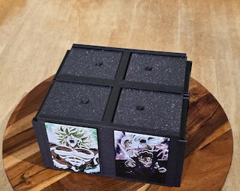 May include: A black, four-compartment box with foam inserts, possibly for storing items. The box sits on a wooden serving tray. The sides of the box feature colorful anime-style character art.