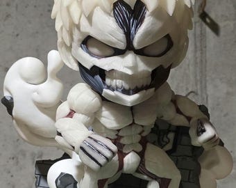 May include: A detailed figurine of a character with a large head, white hair, and a menacing expression. The figure has a muscular build with exposed red muscle details. It is posed on a base with a brick wall and green grass.