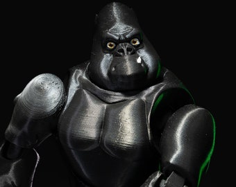 May include: A black articulated gorilla figure with a detailed, textured surface. The gorilla has yellow eyes and a small white tooth. The figure is posed against a black background, highlighting its form and design.