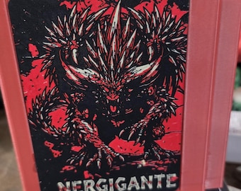 May include: A red rectangular storage box featuring a black and red graphic illustration of the Nergigante creature on the front panel. The text NERGIGANTE is printed in white capital letters at the bottom of the graphic panel on the box.