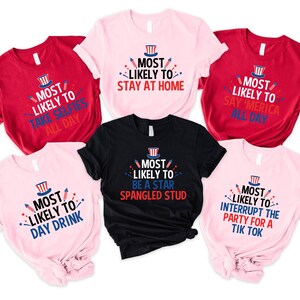 Op de afbeelding: Zes roze en rode T-shirts met een wit en blauw grafisch ontwerp. De shirts hebben verschillende spreuken erop, waaronder "Most Likely to Take Selfies All Day", "Most Likely to Stay at Home", "Most Likely to Say 'Merica All Day", "Most Likely to Day Drink", "Most Likely to Be a Star Spangled Stud" en "Most Likely to Interrupt the Party for a Tik Tok".