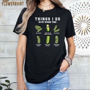 May include: Black t-shirt with the text "Things I do in my spare time" and a series of cartoon pickles with text describing pickle-related activities. The text includes "Eat Pickles", "Hunt for the Perfect Pickles", "Buy Pickles", "Talk About Pickles", "Think About Pickles", and "Dream About Pickles".