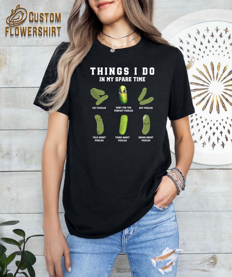 May include: Black t-shirt with the text "Things I do in my spare time" and a series of cartoon pickles with text describing pickle-related activities. The text includes "Eat Pickles", "Hunt for the Perfect Pickles", "Buy Pickles", "Talk About Pickles", "Think About Pickles", and "Dream About Pickles".