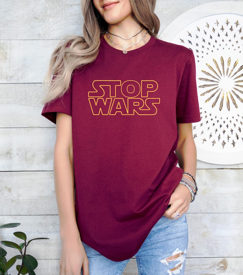 a woman wearing a red shirt with the word stop wars on it