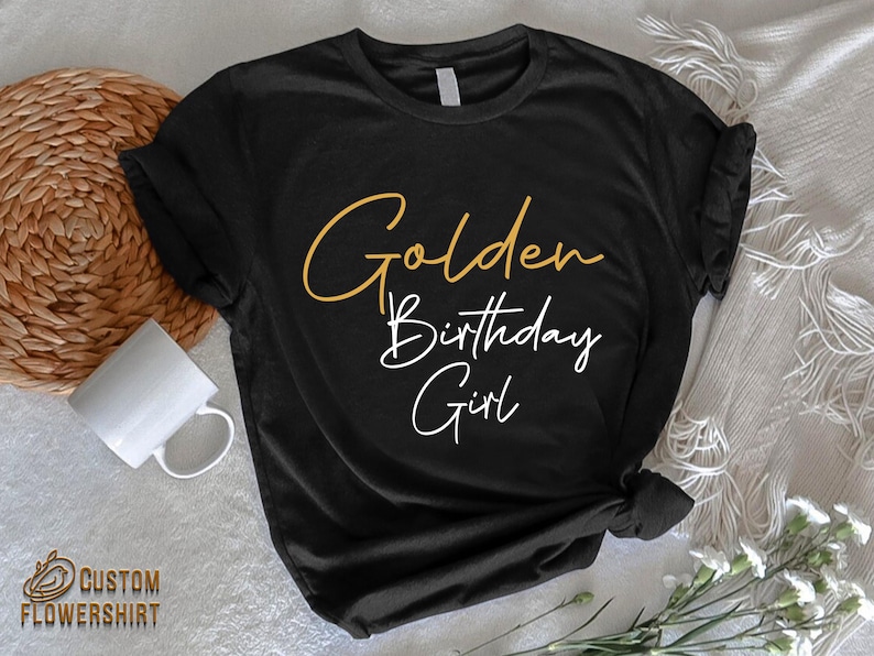 May include: Black t-shirt with the text "Golden Birthday Girl" in gold and white lettering.