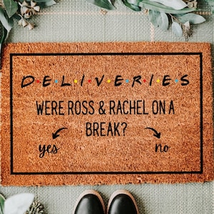 May include: A rectangular doormat with the text "DELIVERIES WERE ROSS & RACHEL ON A BREAK?" in black. The word "DELIVERIES" uses the Friends TV show font. Arrows point to "yes" and "no". Black shoes are at the bottom.