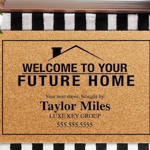 May include: A rectangular doormat made of natural coir fiber. The mat features a black border and text that reads "WELCOME TO YOUR FUTURE HOME." Below the text is "Your next move, brought by: Taylor Miles LUXE KEY GROUP 555.555.5555."