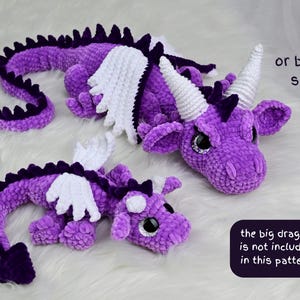 May include: Two purple crocheted dragon plush toys with white wings and horns, and dark purple spines. The larger dragon has white horns, while the smaller one has purple horns. Text reads: or by two sizes and the big dragon is not included in this pattern.