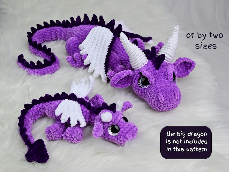 May include: Two purple crocheted dragon plush toys with white wings and horns, and dark purple spines. The larger dragon has white horns, while the smaller one has purple horns. Text reads: or by two sizes and the big dragon is not included in this pattern.