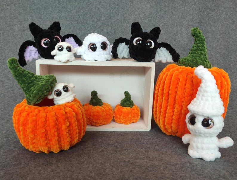 May include: A set of crocheted Halloween decorations, including a black bat, white ghosts, and orange pumpkins. The pumpkins are decorated with green yarn and have a white ghost sitting on top of one.