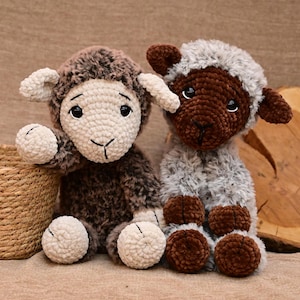 May include: Two crocheted stuffed sheep toys. One sheep is brown with white fur on its face and legs. The other sheep is grey with brown fur on its face and legs.