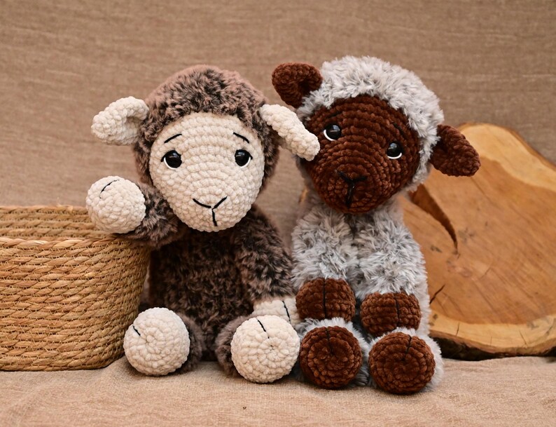 May include: Two crocheted stuffed sheep toys. One sheep is brown with white fur on its face and legs. The other sheep is grey with brown fur on its face and legs.