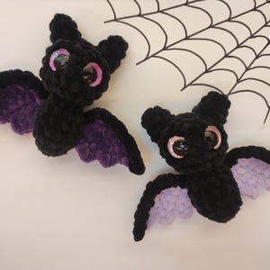 May include: Two black crocheted bats with purple wings and large pink eyes.