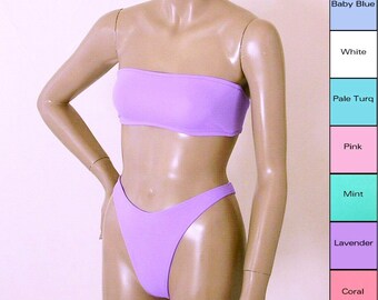 May include: A lavender bandeau bikini top and matching high-cut bikini bottom. The bikini is made of a smooth, stretchy fabric.