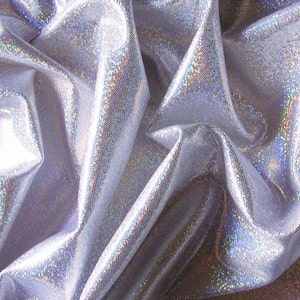 May include: Close-up of a shimmering silver fabric with a textured surface. The fabric is draped, creating folds and shadows that enhance its iridescent quality. The material reflects light, displaying a subtle rainbow effect.