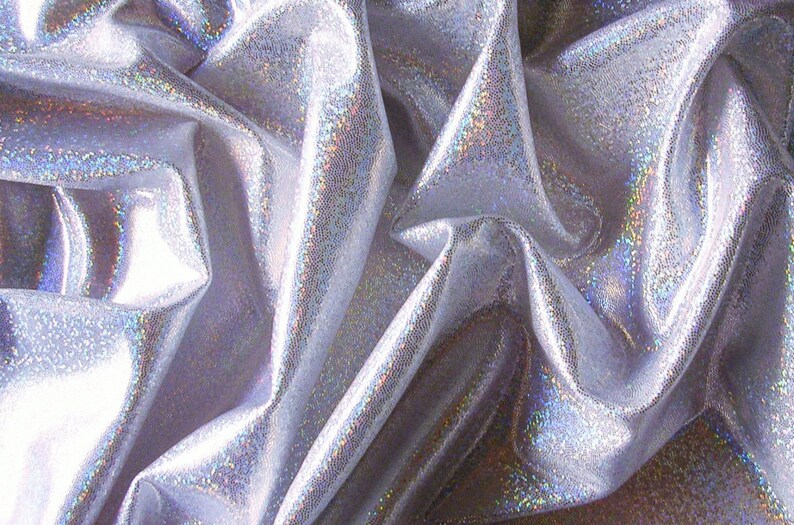 May include: Close-up of a shimmering silver fabric with a textured surface. The fabric is draped, creating folds and shadows that enhance its iridescent quality. The material reflects light, displaying a subtle rainbow effect.