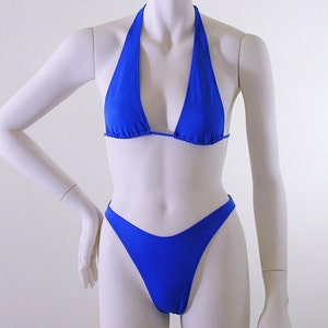 May include: A royal blue bikini top and bottom. The top is a halter style with a triangle shape. The bottom is a high-cut style.