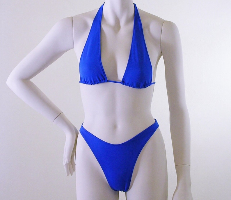 May include: A royal blue bikini top and bottom. The top is a halter style with a triangle shape. The bottom is a high-cut style.