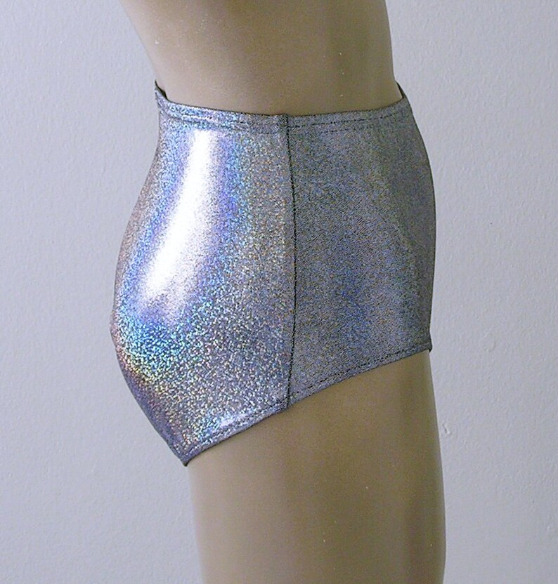 May include: High-waisted silver shorts with a shimmering, iridescent finish. The shorts are made of a shiny, reflective material and have a high-cut leg opening. The shorts are designed to be form-fitting and are likely for dance or performance wear.