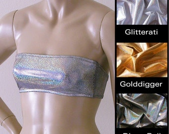 Könnte beinhalten: Ein silbernes Tube-Top mit einem glitzernden, schillernden Finish. Das Oberteil wird auf einer Schaufensterpuppe gezeigt. Das Bild zeigt auch Stoffmuster in Silber, Gold und Schwarz mit den Wörtern "Glitterati", "Golddigger" und "Disco Ball", die unter jedem Muster gedruckt sind.